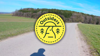 'Walk Wheel Cycle Trust Outsiders' logo with little simple drawings of a winding path surrounded by trees and birds. A dotted line like a plotted route encircles it.